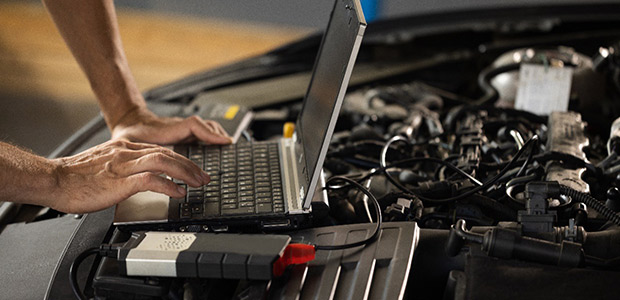 Automechaniker benutzt Laptop bei der Durchführung von Diagnosetests